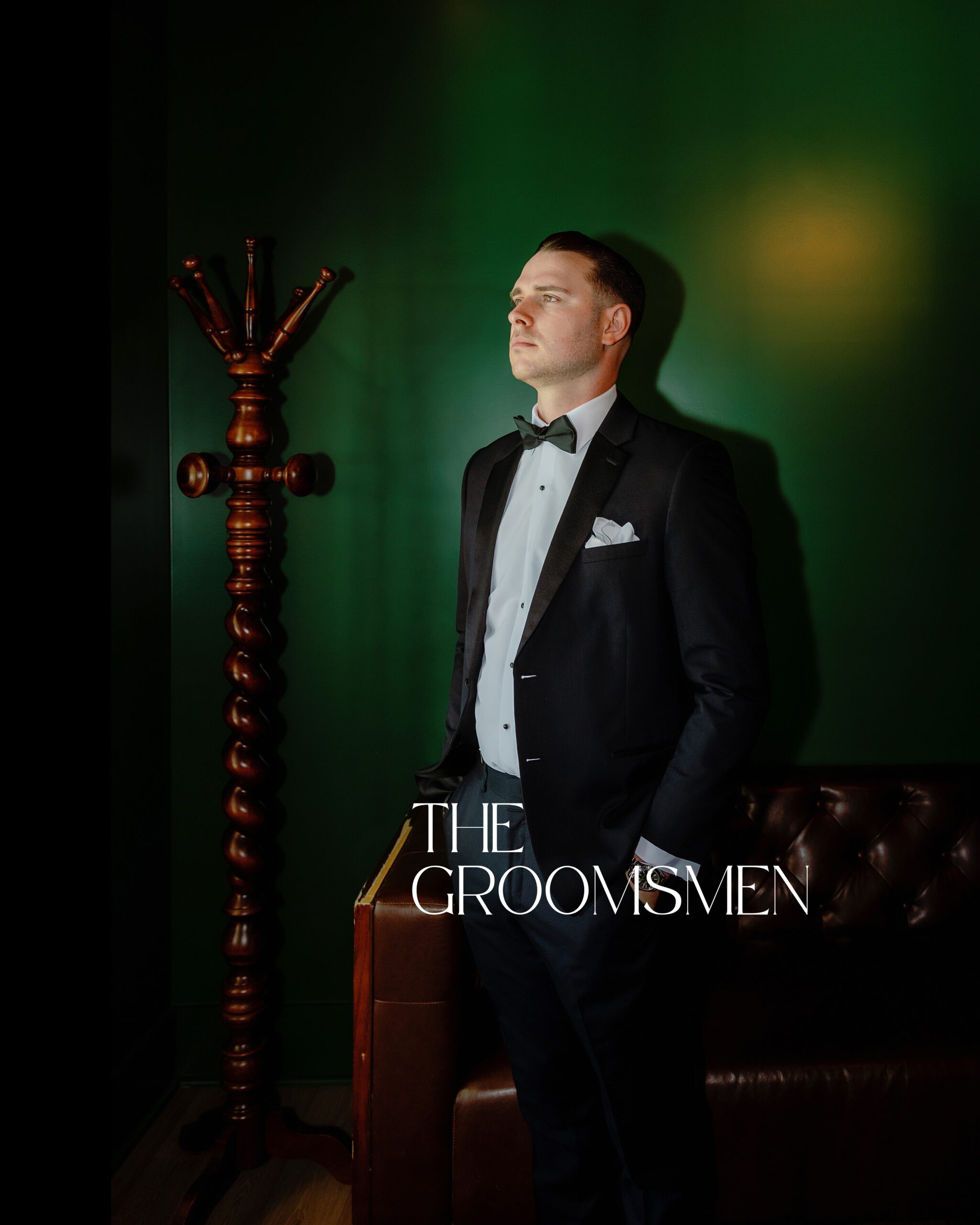 A groom in a tuxedo looking thoughtful in a green cigar lounge right before getting married at Hewitt Oaks