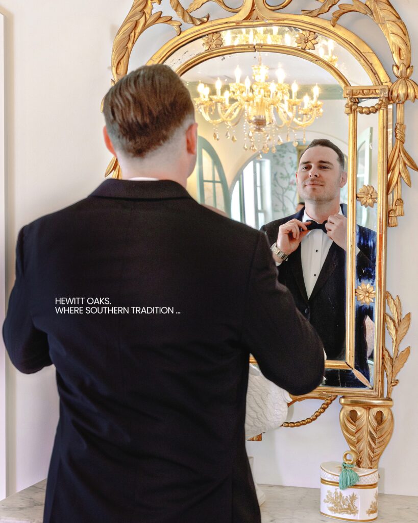 A groom in a tuxedo adjusting his tie in a gilded mirror at Hewitt Oaks