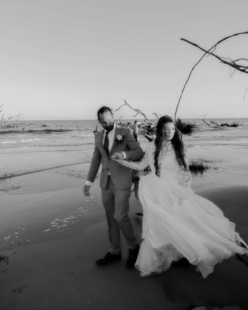 Bride and groom walking hand in hand along the shore of the beach at Hunting Island