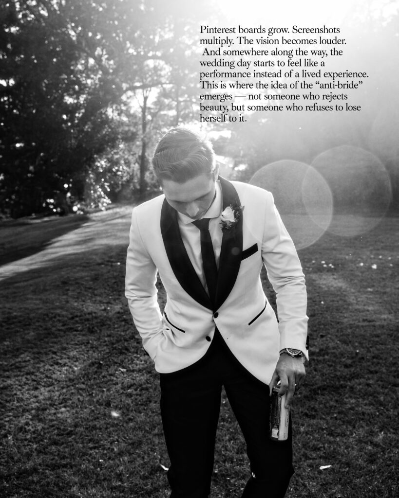 Black and white image of groom walking in a tuxedo with a drink in his hand looking very James Dean