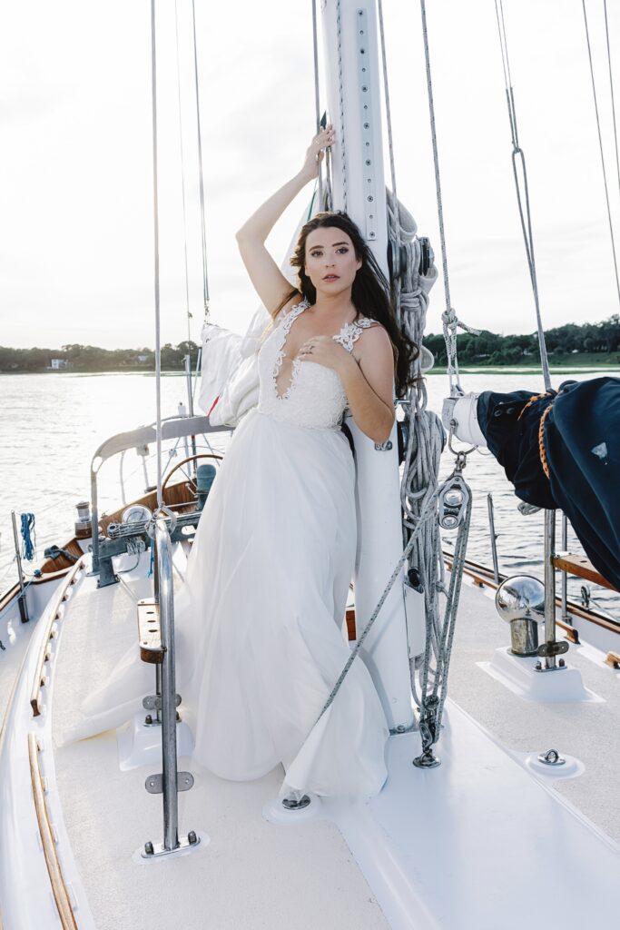 Bride on a sailboat in the Beaufort Harbor posing leaning on the mast