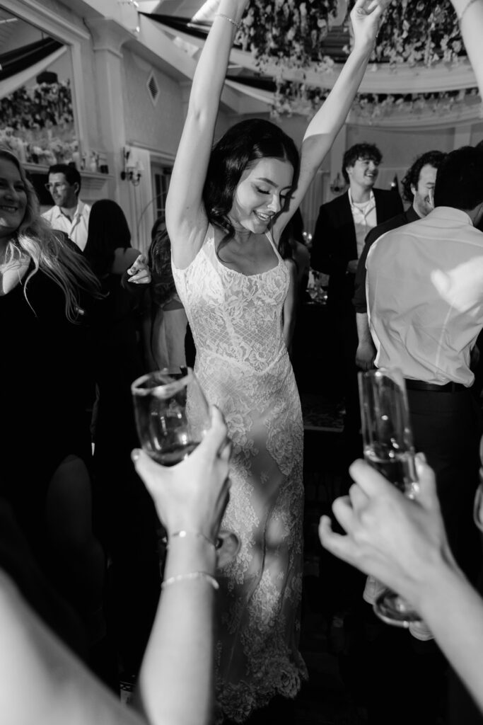 Bride dancing and having fun during her reception at Palmetto Bluff with her hands in the air and a second dress on while others watch around her and toast her