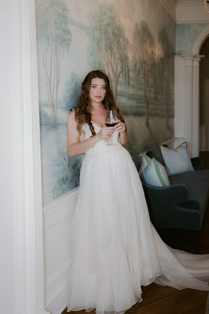Relaxed bride enjoying a glass of wine after getting ready for her wedding at the Cuthbert HOuse Inn