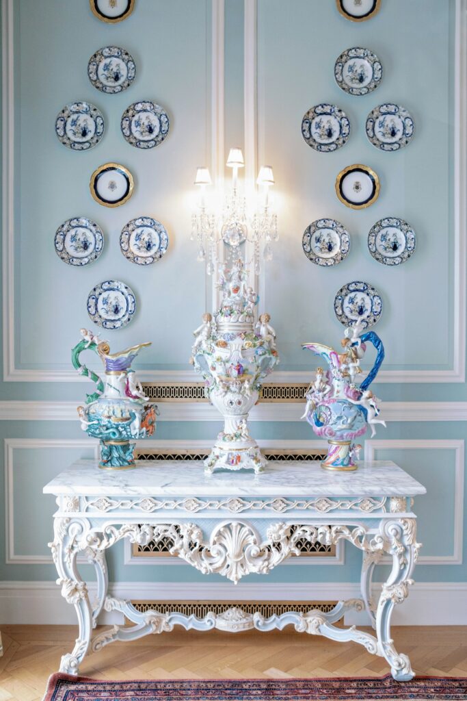A beautiful interior in a french inspired room with with a blue wall and dishes on it in front of a antique french sideboard  at the Armstrong Kessler Mansion in Savannah
